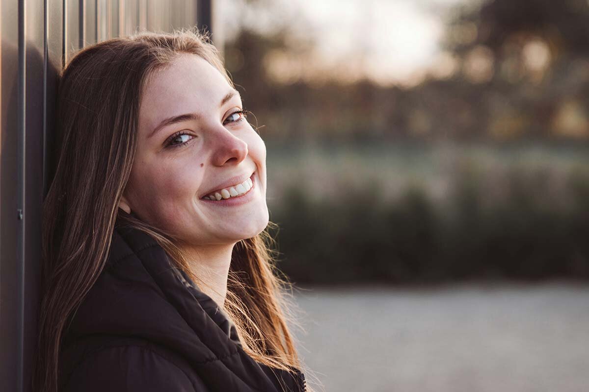 A smiling woman leaning against a wall, having qualified for an instant loan.