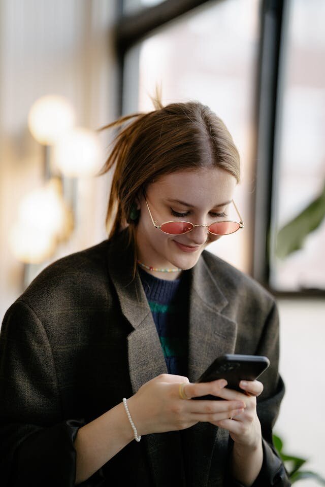Smiling young woman receiving premier loan approval on her phone