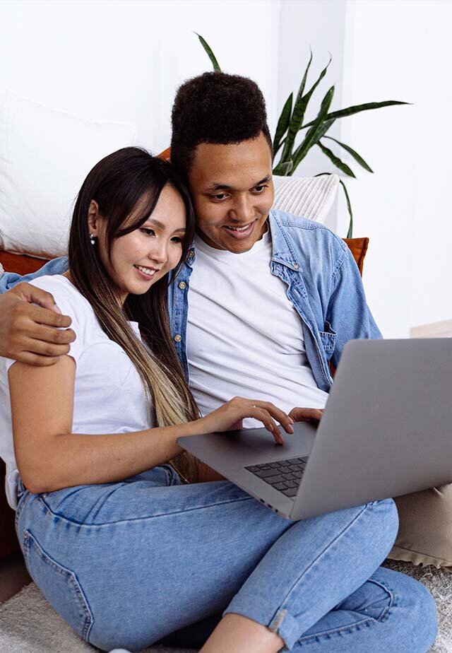 Smiling young couple using laptop computer to research personal installment loans.
