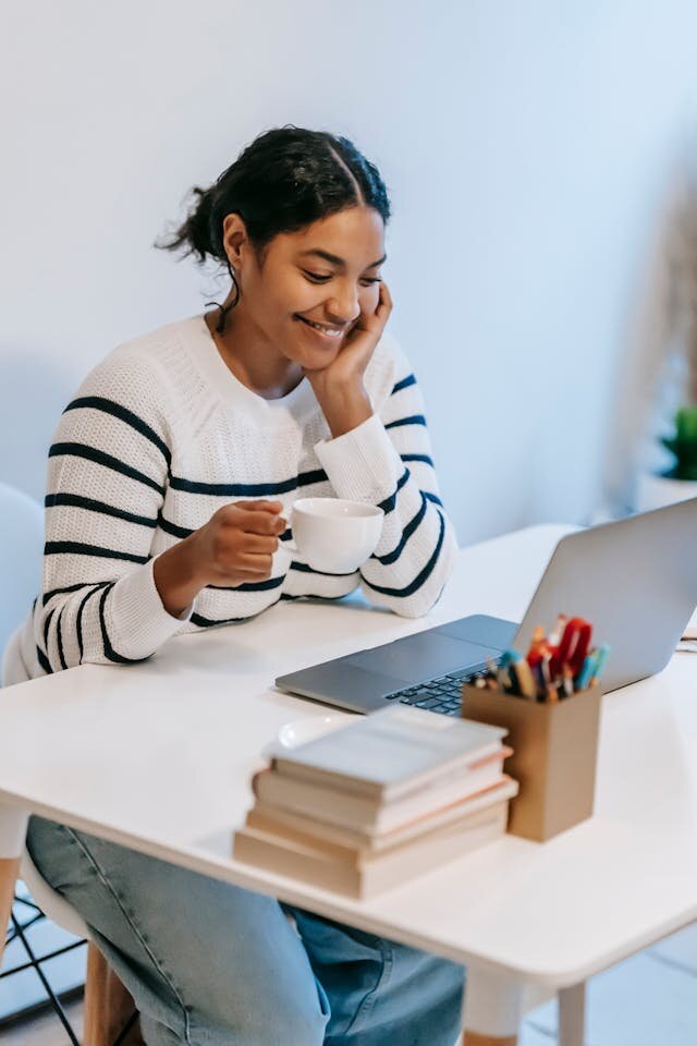 Woman with coffee and using laptop computer to read about a line of credit in Utah