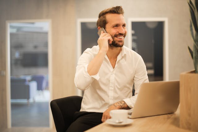 Smiling man with phone and computer applying for an installment loan in Mississippi.