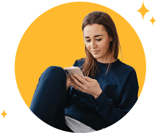 Young woman using mobile phone leaning against pillows