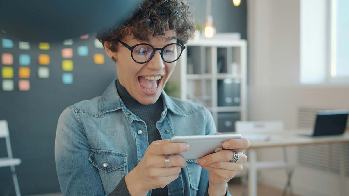 An excited young woman using her phone to free up some funds from her budget.