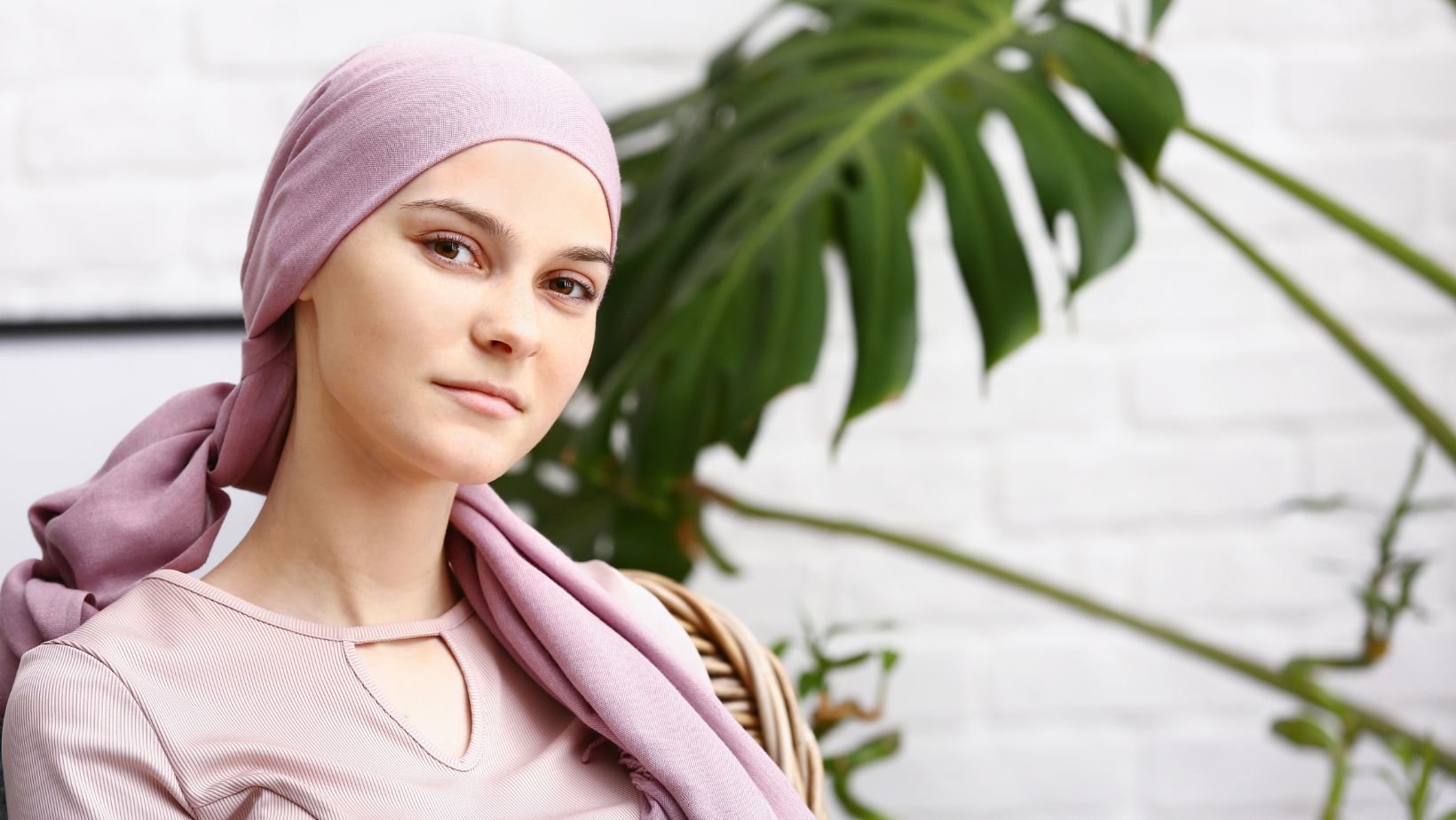 Woman sitting in front of a plant with a scarf on her head