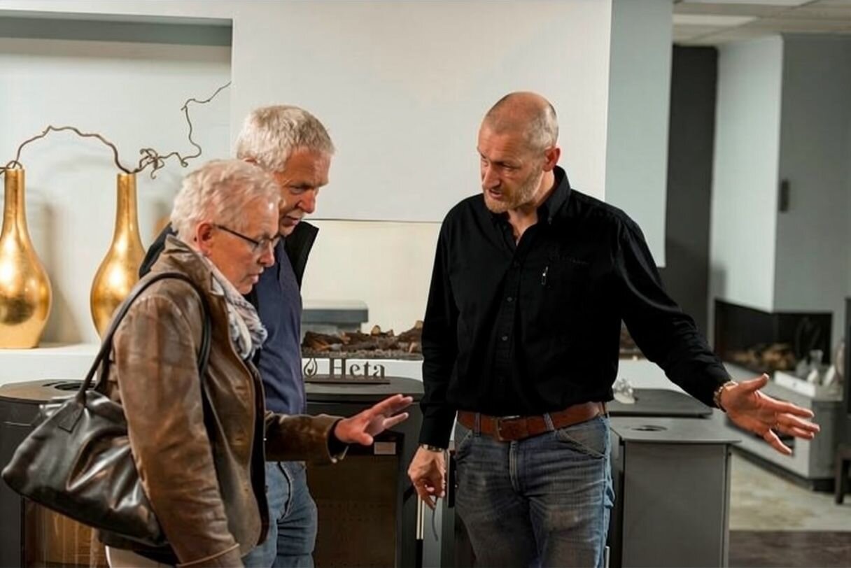 Verkoper geeft deskundig advies in de showroom aan ouder echtpaar