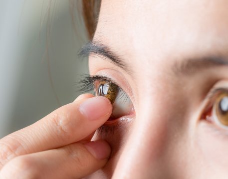 Woman removing a contact lens from her eye