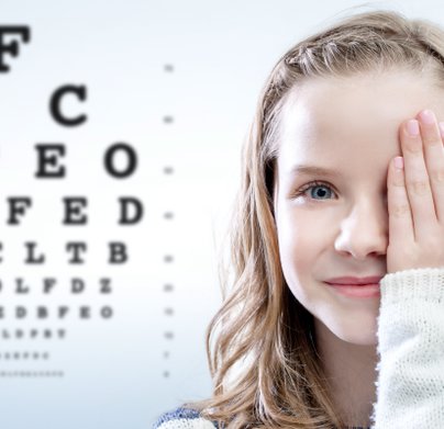 Young girl covering eye with eye test chart in background that is used to check their vision