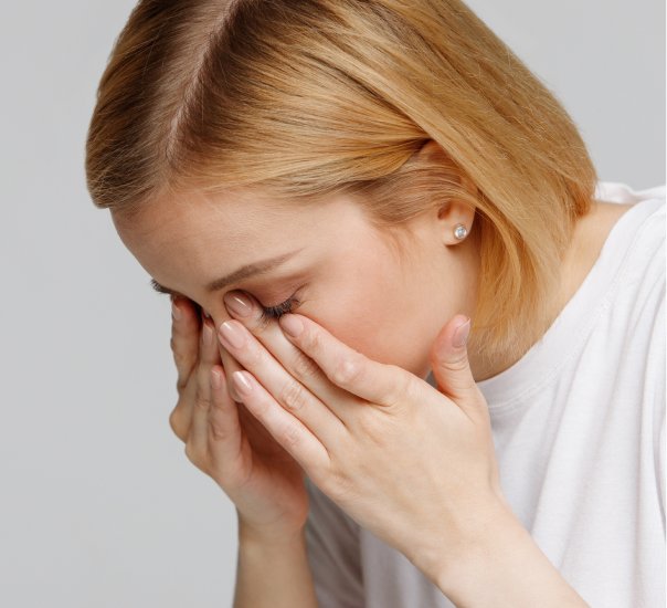 Young woman rubbing painful eyes after an adverse reaction to contact lenses