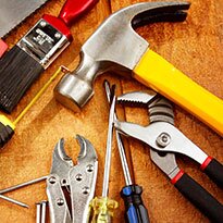 A group of hand tool including screwdrivers, a hammer, pilers, a paint brush and more.