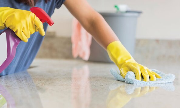 A surface being cleaned, the cleaner wearing yellow gloves.