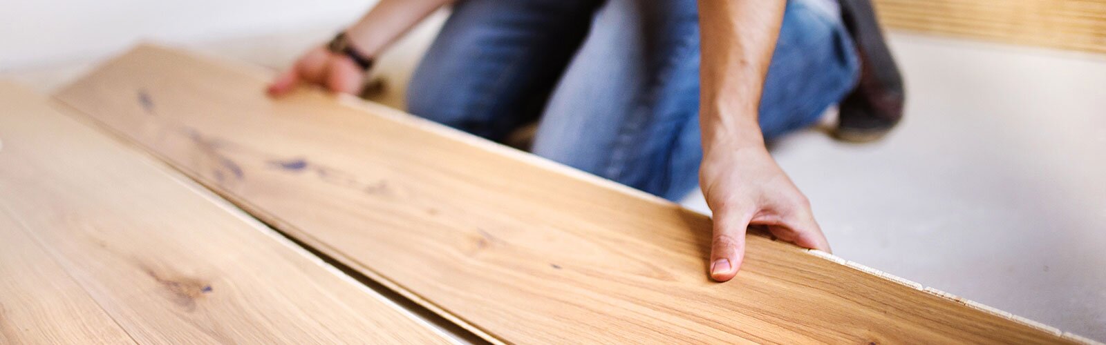 A plank of laminate flooring is being installed. 