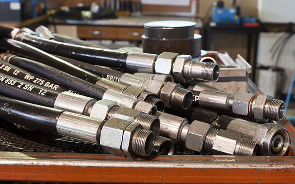 A pile of hydraulic hoses lying on a table in a workshop.