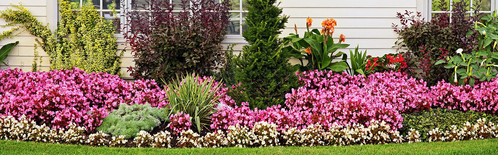 A beautifully taken care of yard with flower beds and gardens.