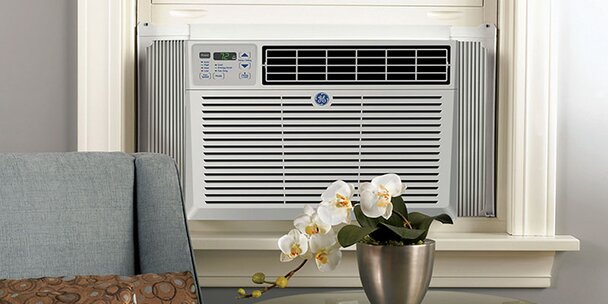 A window air conditioner unit installed in a window, turned on.
