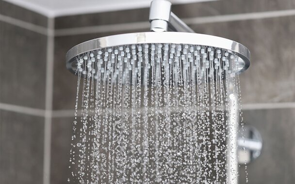 A sleek, rainfall-style shower head turned on.