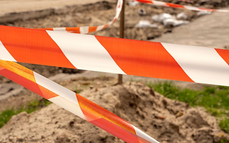 Orange and white safety tape blocking off a construction zone. 