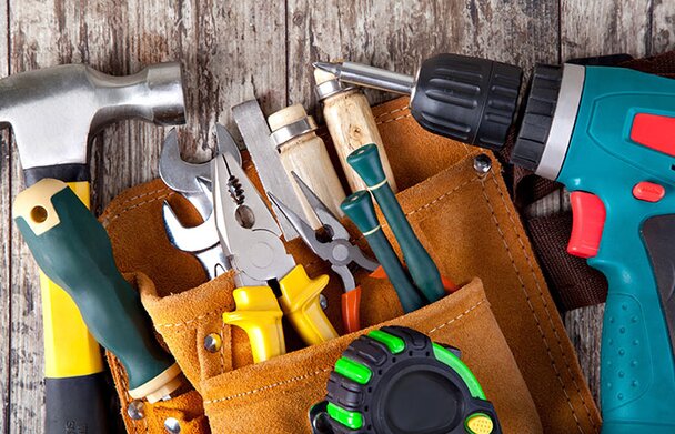 A group of hand and power towls on a wood background with a power drill.