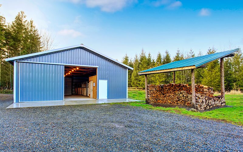Outdoor shed with blue cladding, wood storage off to the side.