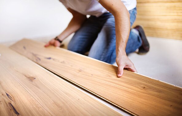 A person installing laminate flooring.