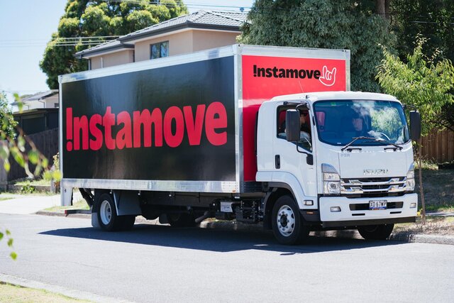 Full side view of an Instamove branded moving truck parked on a residential street