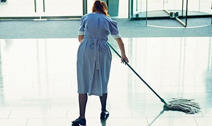 Woman mopping the floor of corporate building