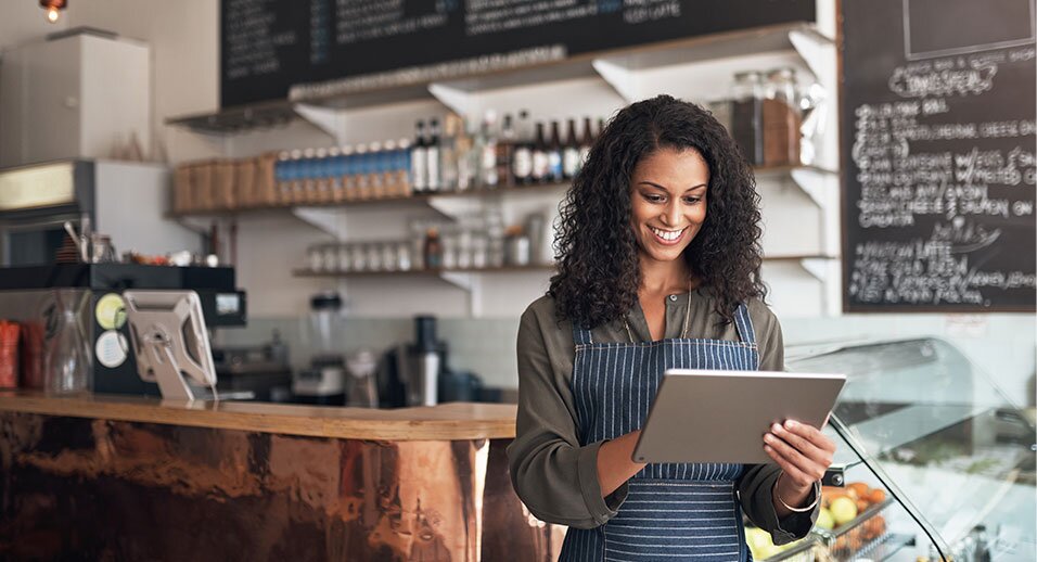 Image of woman in coffee shop reviewing inventory on tablet