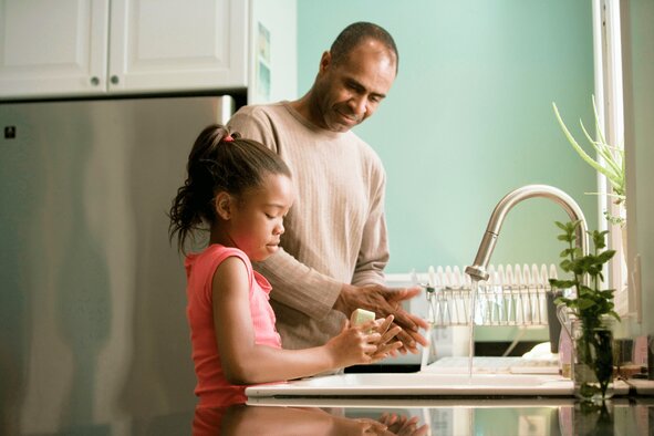 Family washing hands by kitchen sink