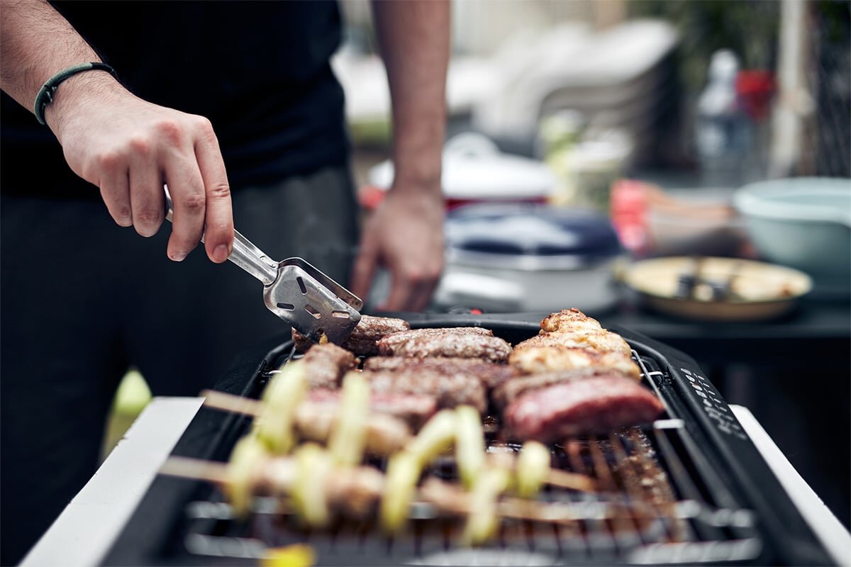 Person cooking outdoors using electric grill