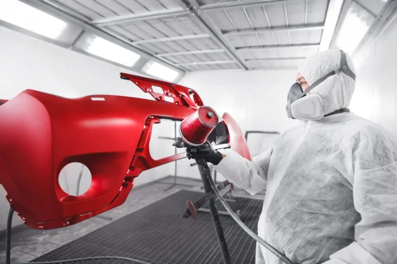 Profissional aplicando pintura em parachoque automotivo na oficina Elite Express