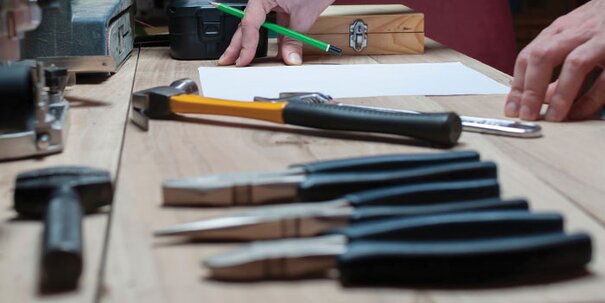 A workbench with hand tools including hammer and pliers.