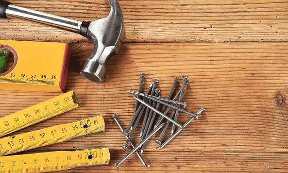 A group of nails and hand tools on a wooden background.