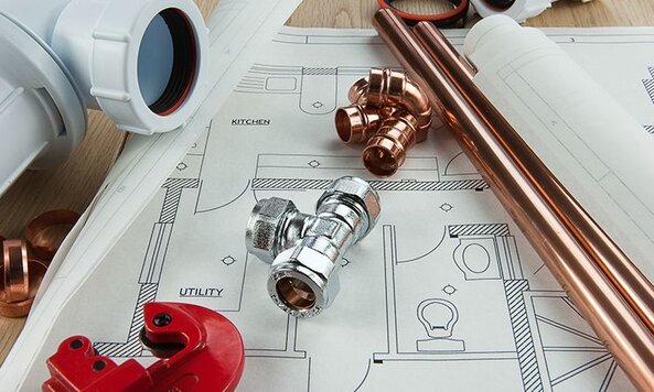 A variety of plumbing supplies lay on top of a blueprint.