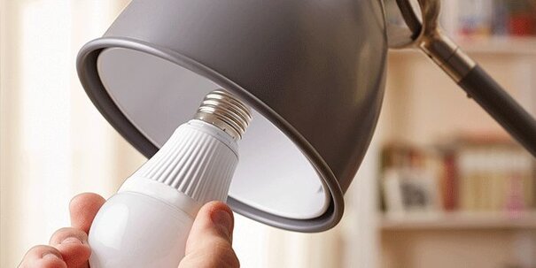 A light bulb on desk lamp being installed.