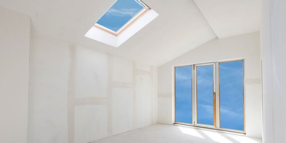 Fresh drywall and plaster in a room with a sliding door and a skylight. 