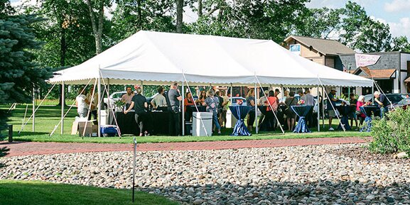 A large white frame tent, captured from a distance, a professional event is taking place.