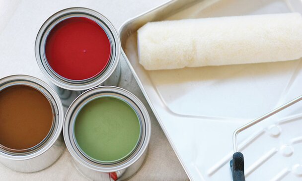 Open paint cans (red, brown, green) and a clean roller and paint tray.