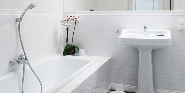 A white, clean, fresh looking bathroom with tub, vanity and an orchid flower in the corner.