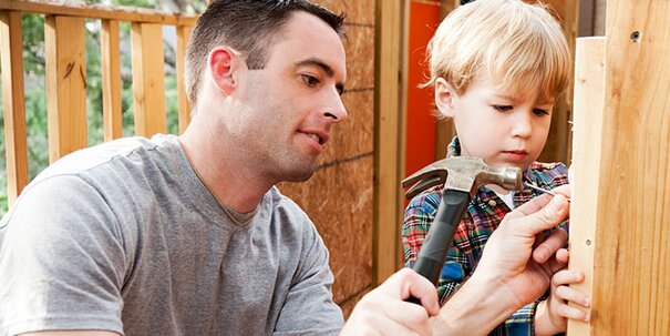 A father and son are working together to build a treehouse. 