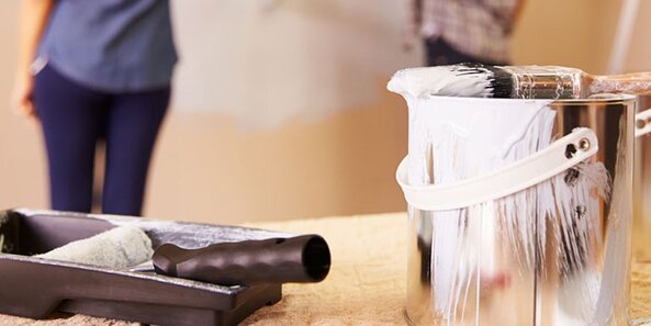 An open can of white paint, and roller.