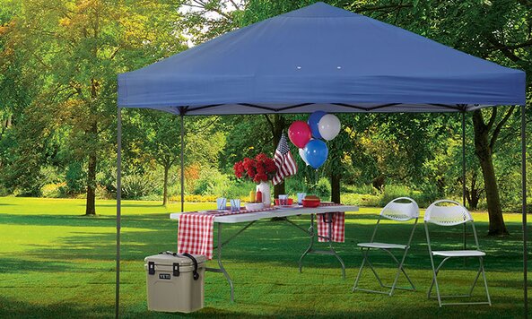 A foldable table and chairs on Fourth of July under a tent.
