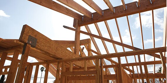 A roof truss and framing lumber of a new house are being constructed.