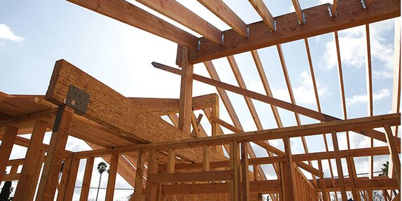 A roof truss and framing lumber of a new house are being constructed.