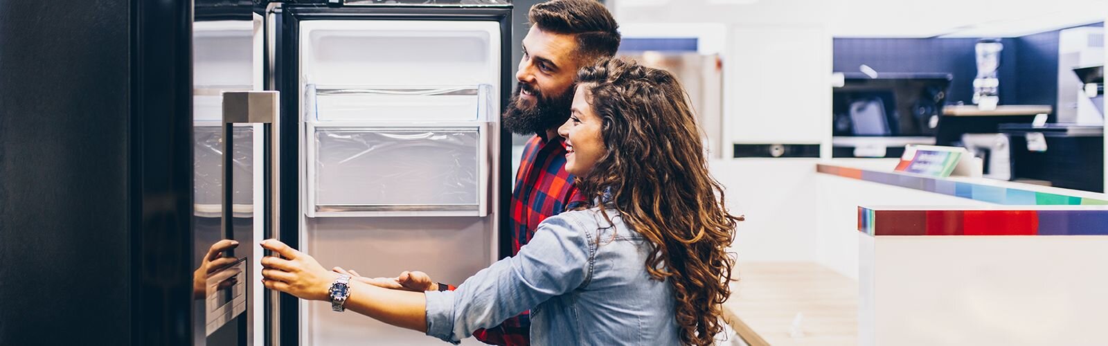 A happy couple shopping for a new fridge.