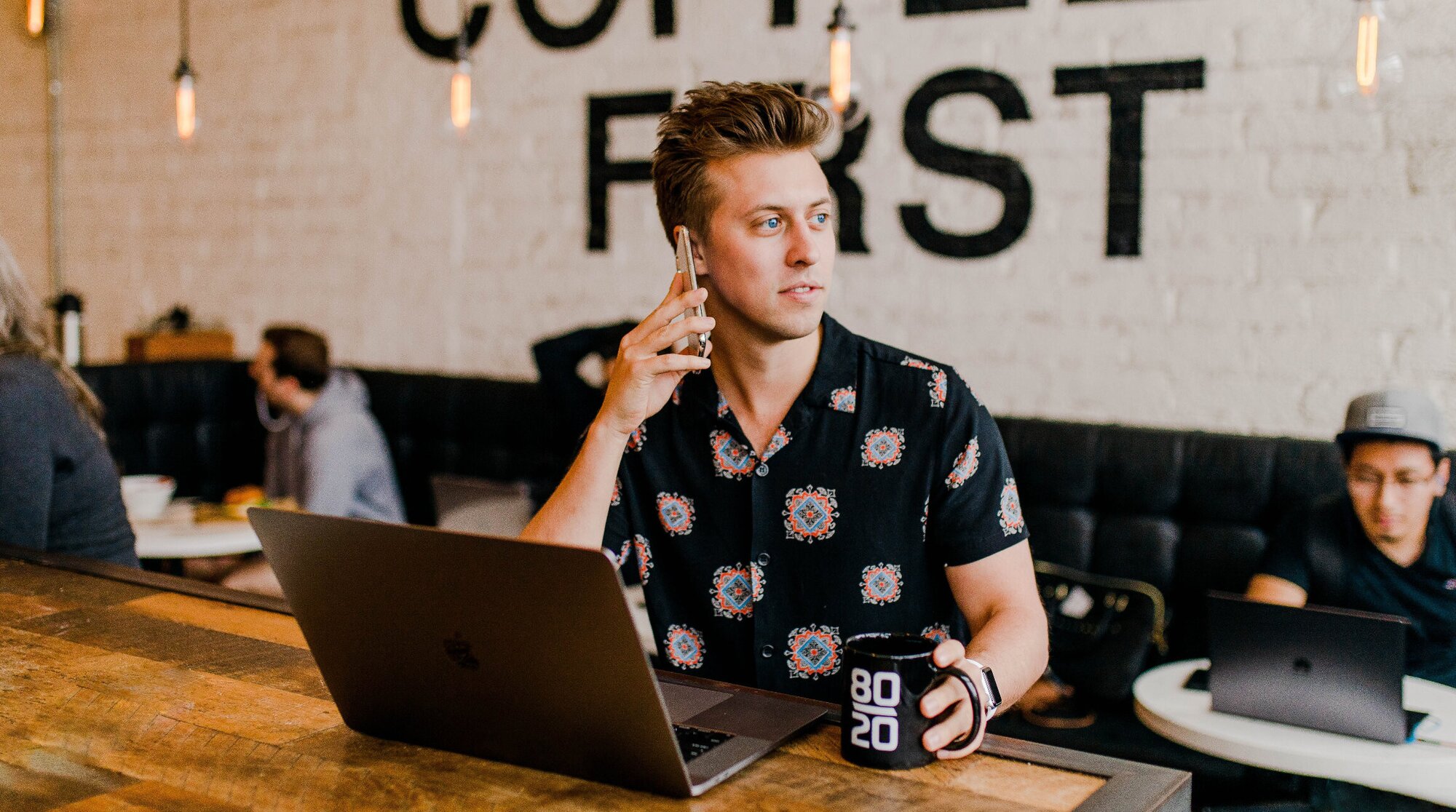 man working in a coffee shop and talking on his phone