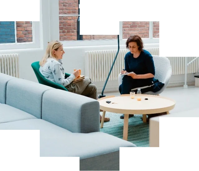 Two women sitting in lounge chairs at an office