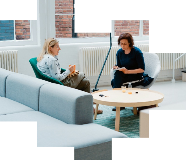Two women sitting in lounge chairs at an office