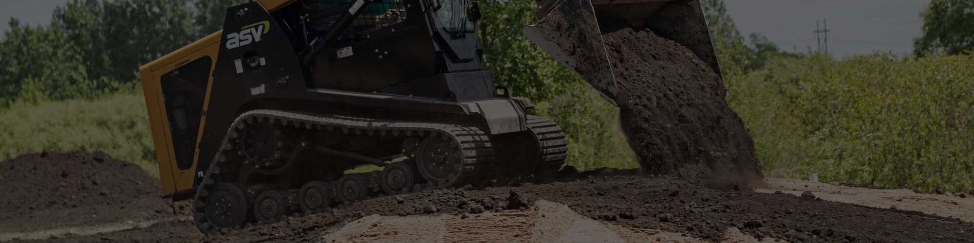 A track loader with a bucket attachment dumping dirt on an existing pile