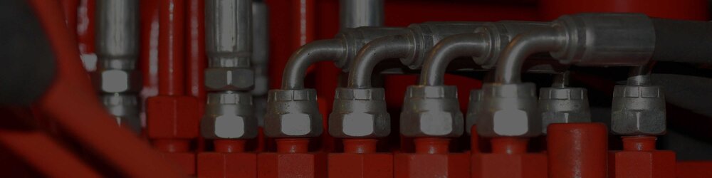 Silver hydraulic fittings connected to a bright red component