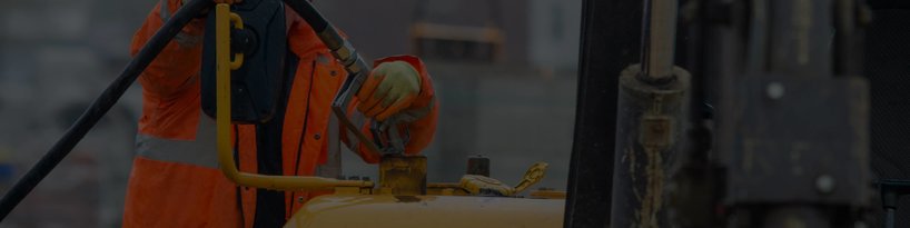A technician adding diesel fuel to a piece of heavy equipment