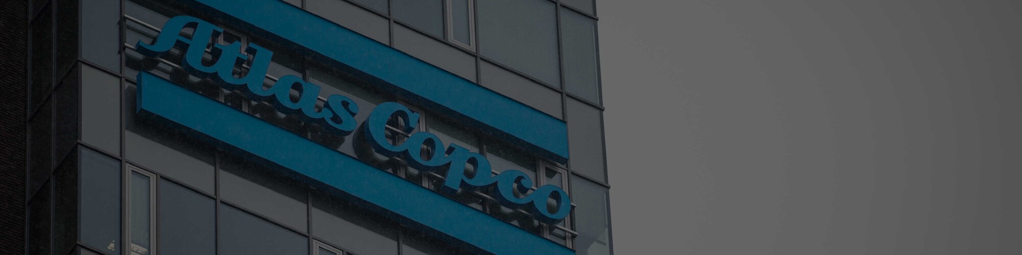 A blue Atlas Copco sign on the site of a building 